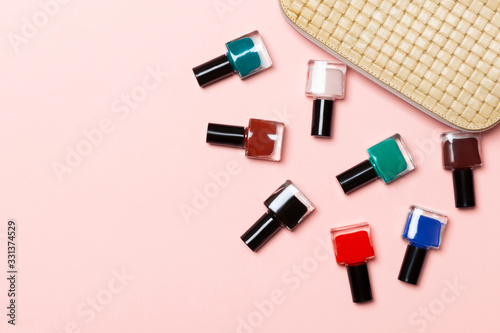 Fototapeta Naklejka Na Ścianę i Meble -  Top view of the set of nail polishes and bright gel varnishes fallen out of cosmetics bag with copy space on pink background. Trendy nail concept