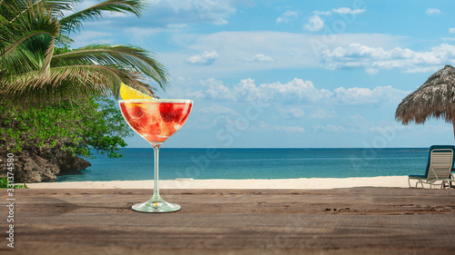 Fototapeta Naklejka Na Ścianę i Meble -  Raspberry. Summer bright and tasty refreshing cocktail with sea or ocean beach with palms and white sand on background. Yellow alcohol drink with berries. Concept of summertime, vacation, resort