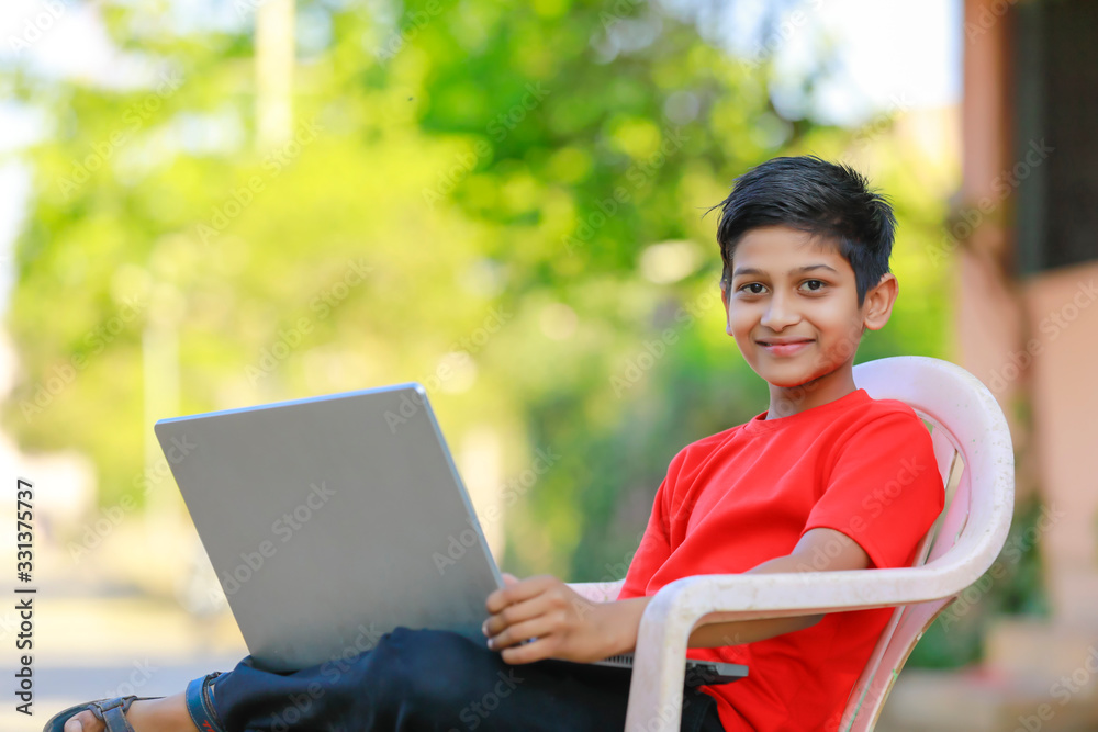 Cute little Indian/Asian boy studying or playing game with laptop computer Cute little Indian/Asian boy studying or playing game with laptop computer