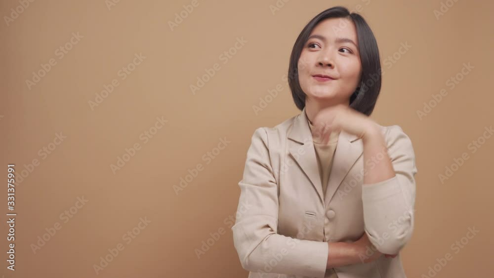 Confident asian business woman happy standing and pointing to copy space isolated over beige background. 4K video Confident asian business woman happy standing and pointing to copy space isolated over beige background. 4K video