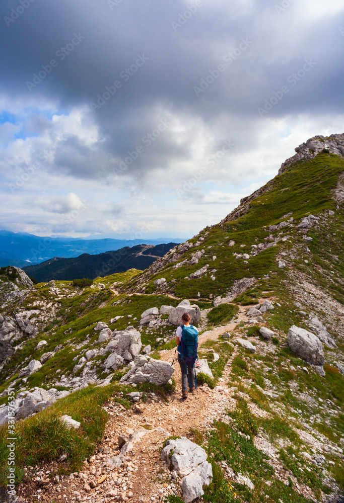 Young woman with backpack hiking along the path in the Vogel mountain, Slovenia
