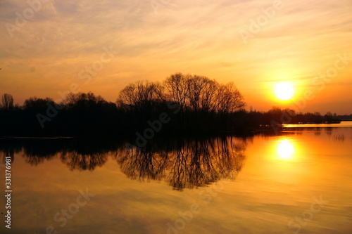 A wonderful Golden sunrise over the river with trees in spring. © HENADZ