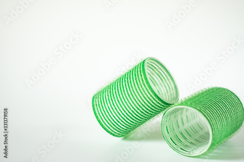Close-up of two green hair curlers on a white background.