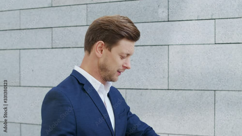 Businessman walking on street. Male executive checking wristwatch outside Businessman walking on street. Male executive checking wristwatch outside