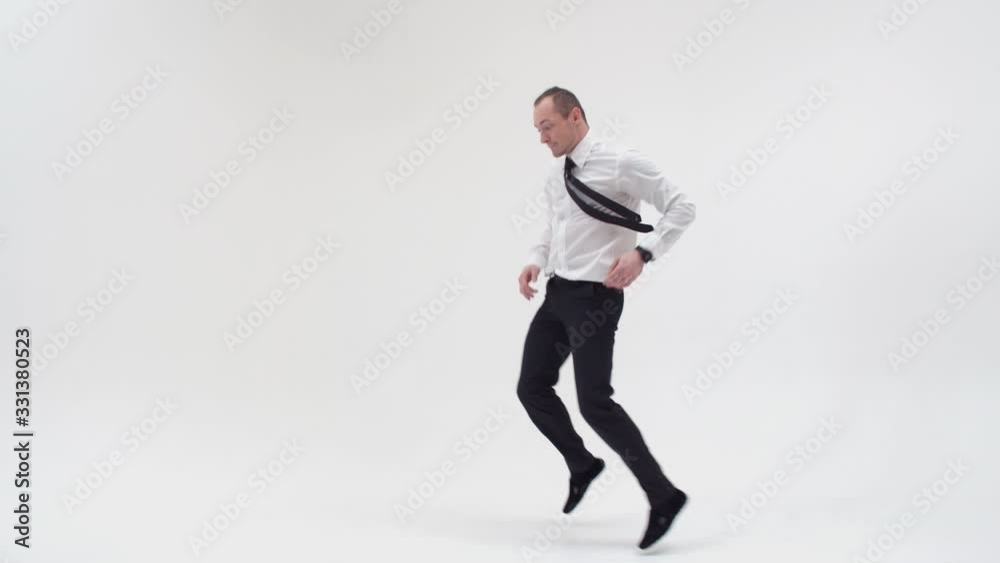 A guy in a shirt and trousers dances the bottom break and stands on one hand, holding the other leg. Bottom break with handstand on white background A guy in a shirt and trousers dances the bottom break and stands on one hand, holding the other leg. Bottom break with handstand on white background