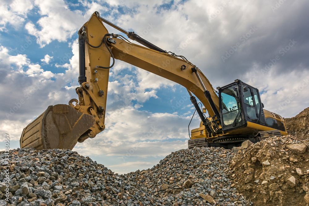 Excavator on a mountain of gravel in a quarry Excavator on a mountain of gravel in a quarry