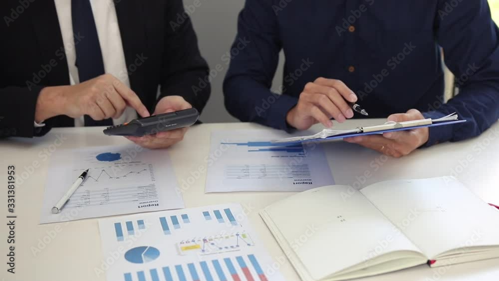 Managers and employees are calculating earnings on paper that contains graph data in the chart report and using calculators and collaboratively analyzing at the office. Managers and employees are calculating earnings on paper that contains graph data in the chart report and using calculators and collaboratively analyzing at the office.
