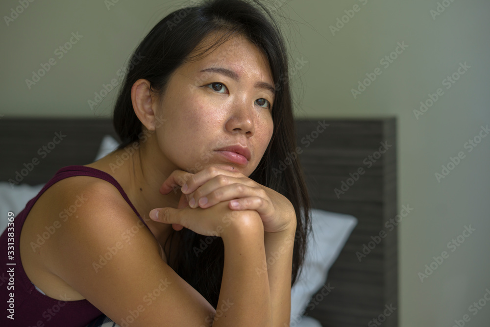 lifestyle indoors portrait of young attractive sad and depressed Asian Korean woman at home sitting on bed emotional and thoughtful feeling worried and scared about life problem lifestyle indoors portrait of young attractive sad and depressed Asian Korean woman at home sitting on bed emotional and thoughtful feeling worried and scared about life problem