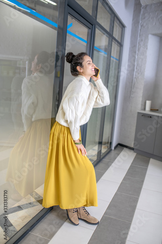 Young woman leaning on glass wall  talking on mobile phone