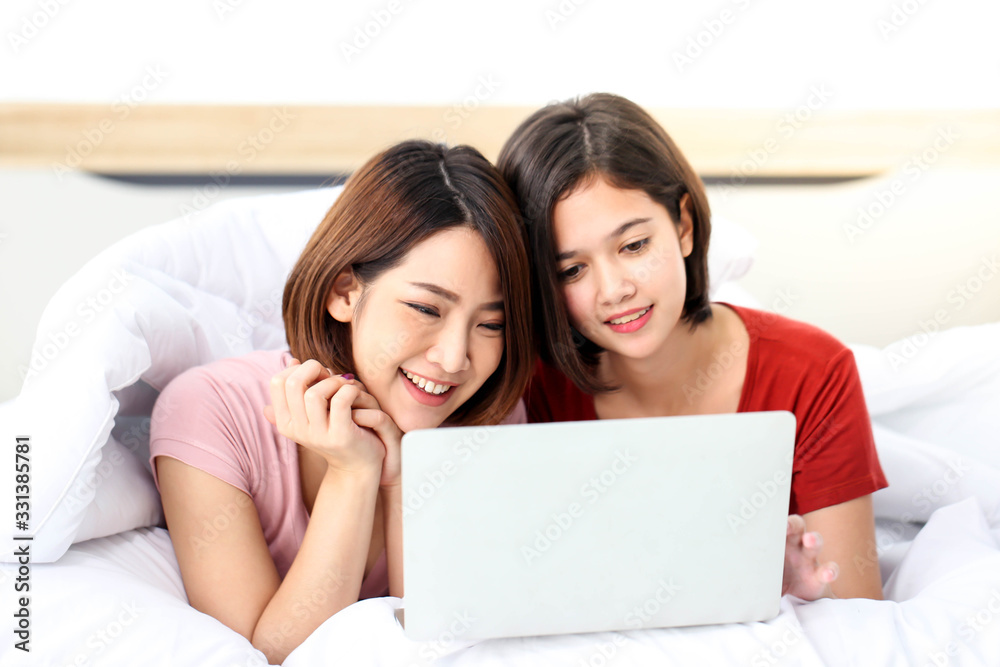 Happy young couple friend beautiful asia women lying on the bed in a bedroom and using digital tablet. Happy young couple friend beautiful asia women lying on the bed in a bedroom and using digital tablet.