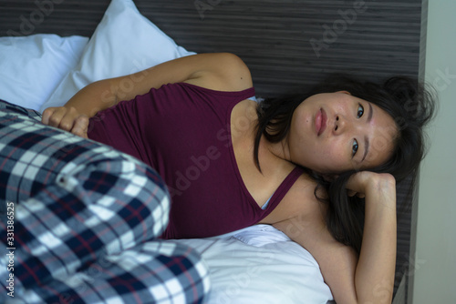lifestyle indoors portrait of young attractive sad and depressed Asian Korean woman at home lying on bed emotional and thoughtful feeling worried and scared about life problem