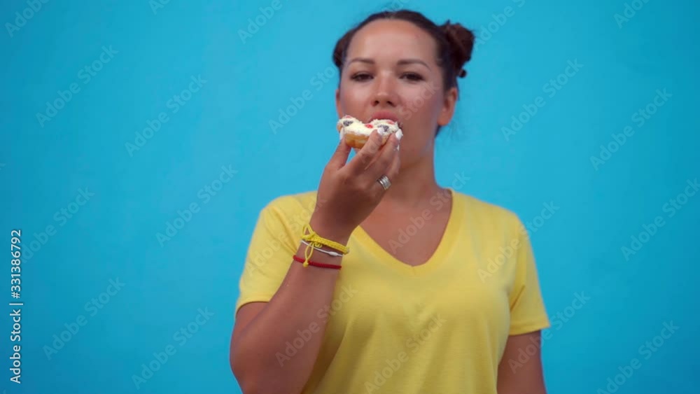 Woman eating donuts at a blue wall background
