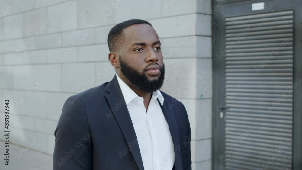 Afro businessman walking on street alone. African male manager going around city Afro businessman walking on street alone. African male manager going around city