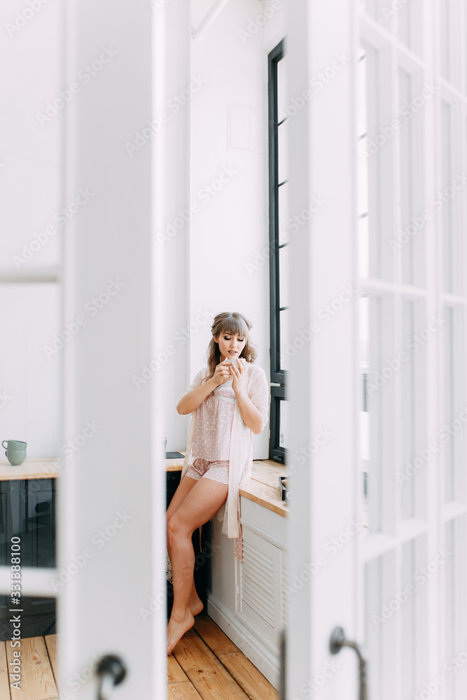 Morning breakfast, beautiful cute cute girl in home pajamas, dressing gown , making coffee sitting on the windowsill in a modern kitchen, weekend vacation, eco, freelance, comfort, spring Morning breakfast, beautiful cute cute girl in home pajamas, dressing gown , making coffee sitting on the windowsill in a modern kitchen, weekend vacation, eco, freelance, comfort, spring