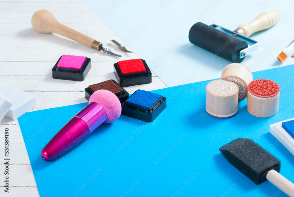 stamp ink pad, lino cutter , papers and rubbers on white wood table stamp ink pad, lino cutter , papers and rubbers on white wood table