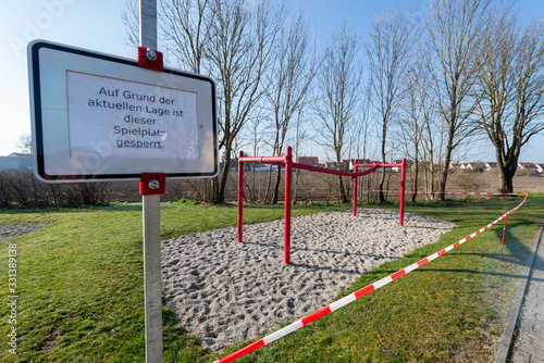 Verbotsschild und rot-weisses Absperrband an einem gesperrten Kinderspielplatz während der Corona-Krise in Deutschland