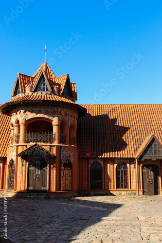 The facade of a gothic mansion. Gothic style architecture built of red bricks. Beautiful estate with a tiled roof.