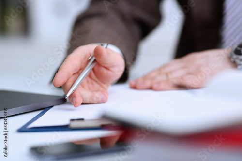 Male arm in suit and tie hold silver pen filling schedule in notepad at office workplace closeup. Legal law consult assistance gesture or finance investment advisor clerk job information gesture © H_Ko