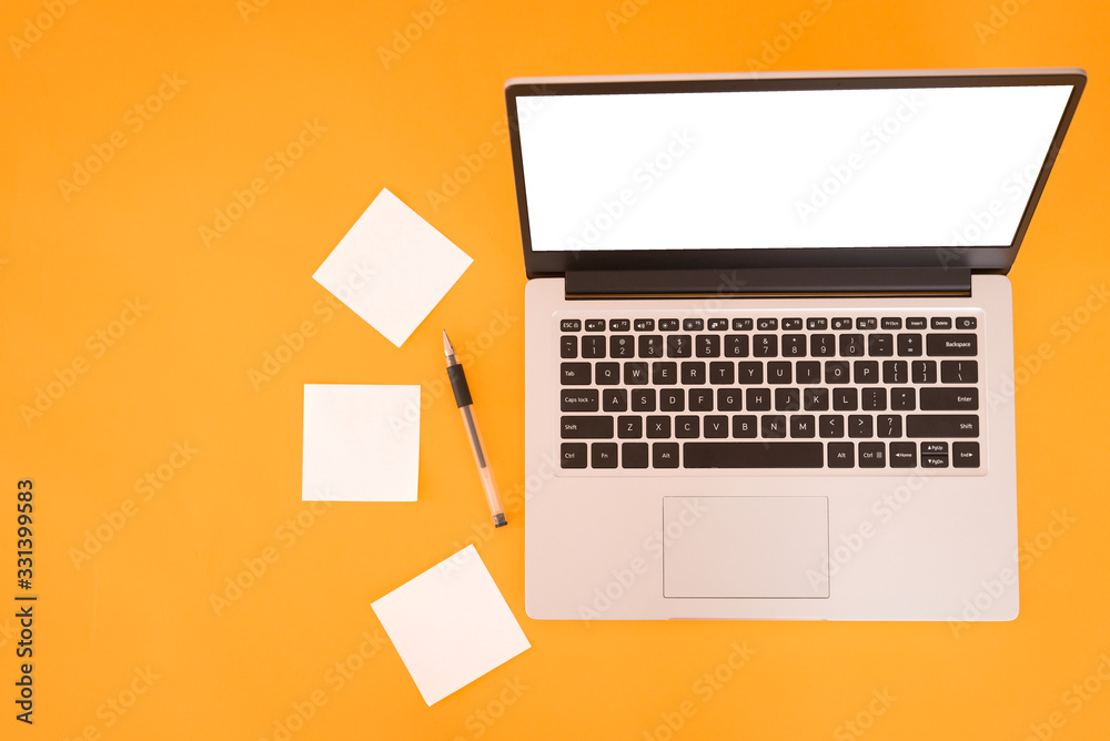 Top view of a business working place with sticky notes and pen, empty workspace on yellow table background. Place for text on a laptop screen Top view of a business working place with sticky notes and pen, empty workspace on yellow table background. Place for text on a laptop screen