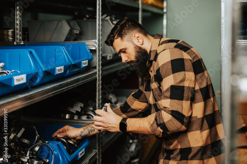 Handsome adult man working in car and truck spare parts warehouse.
