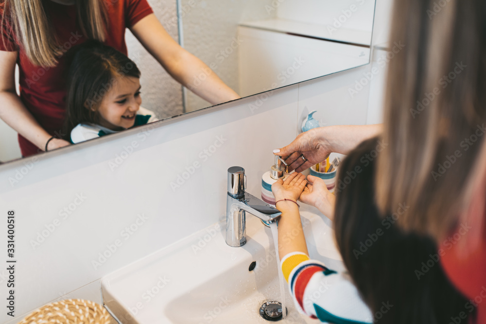 Coronavirus COVID-19 concept. Mother and daughter are washing their hands in bathroom with antibacterial soap.