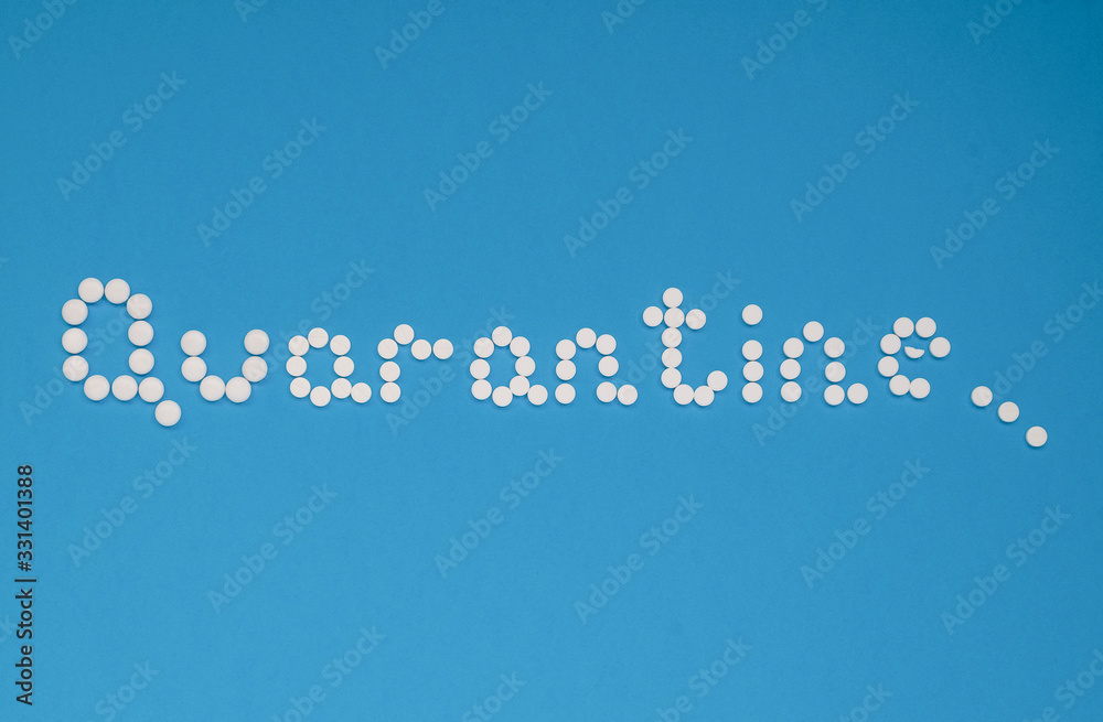 Fototapeta premium The word quarantine, laid out with white tablets on a blue background horizontally. Coronavirus, quarantine concept. Selective focus. Horizontal orientation. View from above.