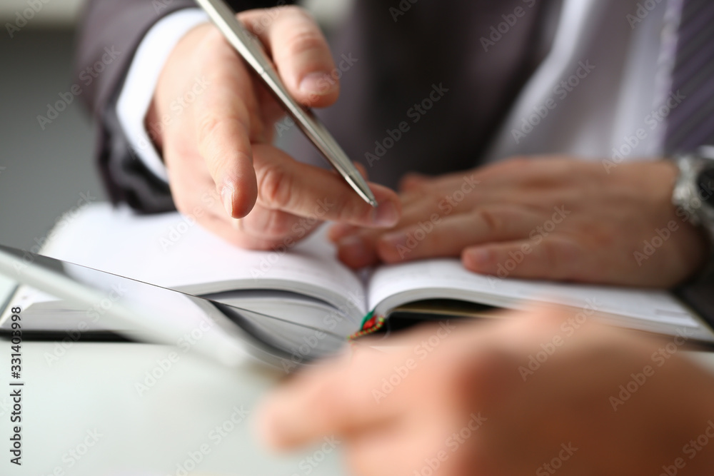 Hand of businessman in suit filling and signing with silver pen partnership agreement form clipped to pad closeup. Management training course some important document, team leader ambition concept