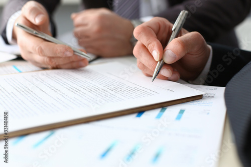 Male arm in suit and tie fill form clipped pad with silver pen closeup. Sign gesture read pact sale agent bank job make note loan credit mortgage investment finance executive chief legal teamwork law photo