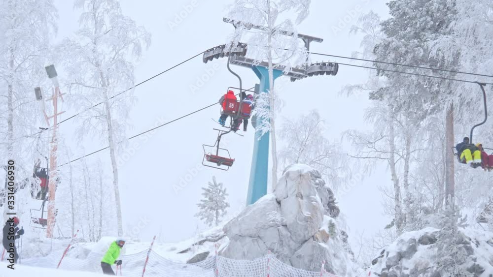 People in outerwear riding modern cableway on mountain slope on cold winter day on ski resort People in outerwear riding modern cableway on mountain slope on cold winter day on ski resort