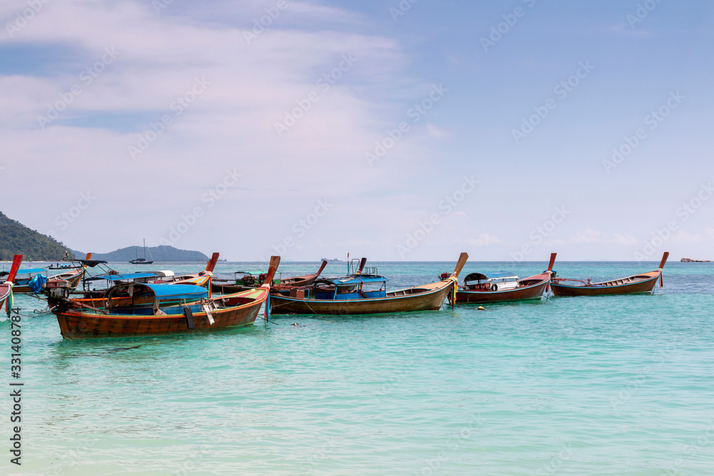 Thai traditional wooden long-tail boat and beautiful sand beach. Longtail boat on tropical island in Thailand. Tropical beach, longtail boats, Andaman Sea.