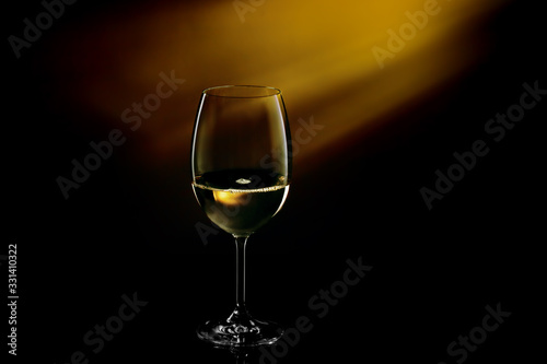 Glass filled with white wine on a gradient background. Close-up studio shot.