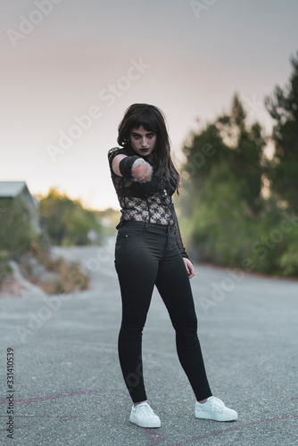chica vestida de negro con el bate de The Walking Dead, en un descampado y diferentes poses para transmitir diferentes sensaciones y/o emociones.