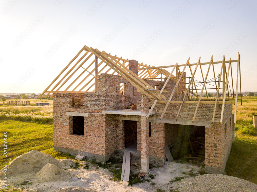 Unfinished brick house with wooden roof structure under construction. Unfinished brick house with wooden roof structure under construction.