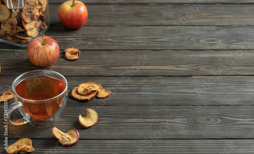 Healthy fruit drink - compote (stewed apple drink) in the cup. Dried apples and ripe apples on a dark wooden table. Close-up, space for text. Traditional folk drink.