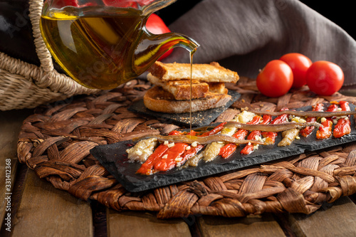 Fototapeta Naklejka Na Ścianę i Meble -  Escalivada washed down with virgin olive oil and vegetables in wicker basket on the rustic wooden table.