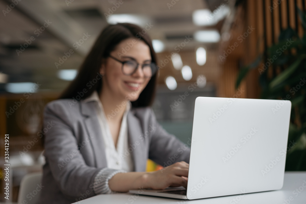 Blurred image of businesswoman using laptop computer, watching training courses, focus on laptop. Beautiful woman freelancer working at workplace, typing, searching on website. Copy space Blurred image of businesswoman using laptop computer, watching training courses, focus on laptop. Beautiful woman freelancer working at workplace, typing, searching on website. Copy space
