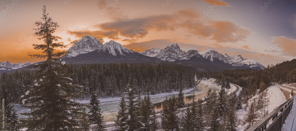 Panorama of famous Morant's curve close to Lake Louise in Alberta, Canada on a beautiful sunny winter evening. Tracks next to a river are seen.