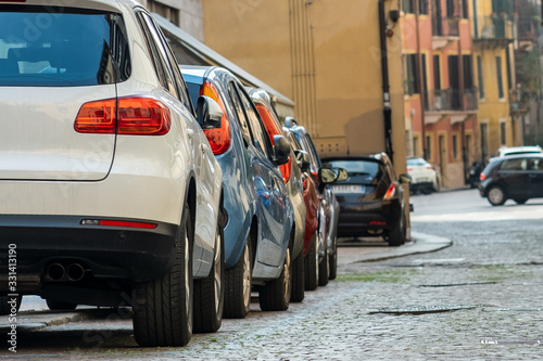 Modern cars parked on city street side in residential discrict. Shiny vehicles parked by the curb. Urban transportation infrastructure concept.