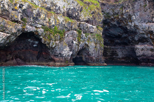 Cave in a cliff and turquoise water in a Akaroa, Banks Peninsula, South Island, New Zealand