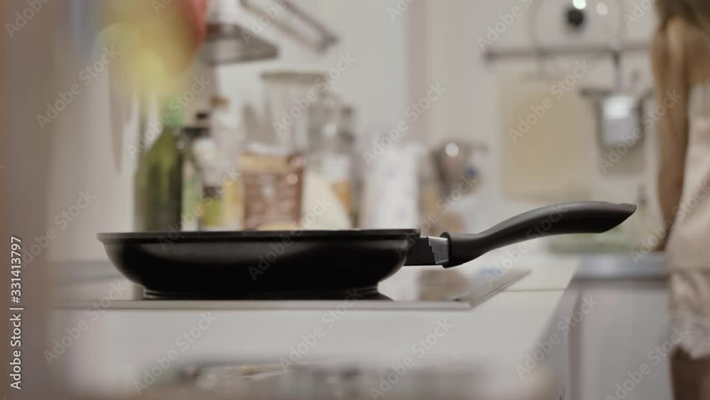 Pan on the stove, a girl in pajamas washes dishes in the background Pan on the stove, a girl in pajamas washes dishes in the background