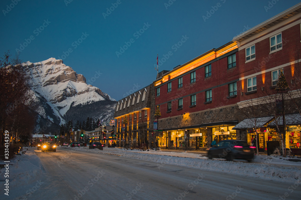 Main road through the city of Banff in Canada on a cold winter evening. Magical lights and majestic sky just after sunset.