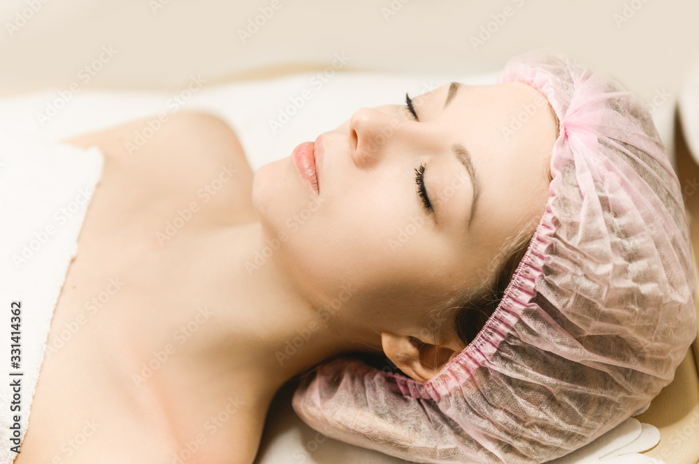 Naklejka premium Close-up portrait of an attractive girl at the reception of a cosmetologist and plastic surgeon, cosmetology, wrinkle removal, facial massage