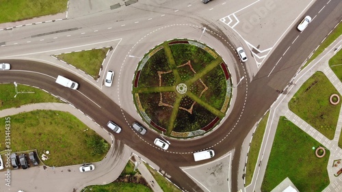 Cars after rain drive on the roundabout road aerial top down view