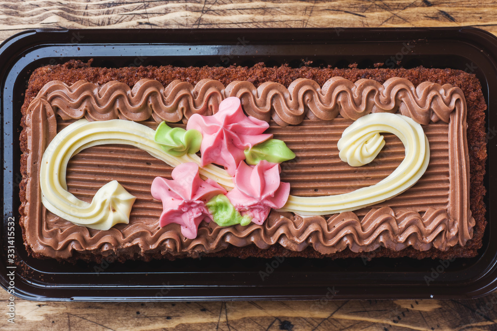 Chocolate rectangular cake decorated with cream roses. Sweet food is a confectionery business. Top view
