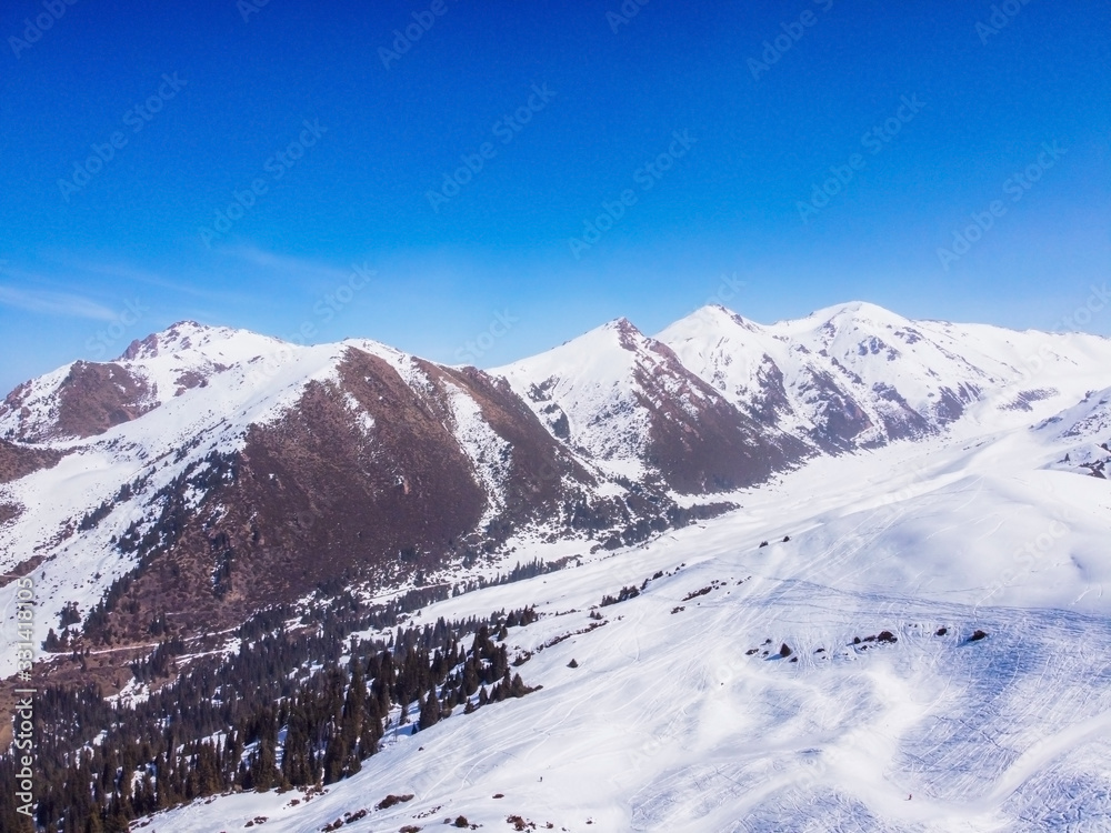Areal view of winter mountains and blue sky. Landscape. Winter Nature. Flight over ski base.