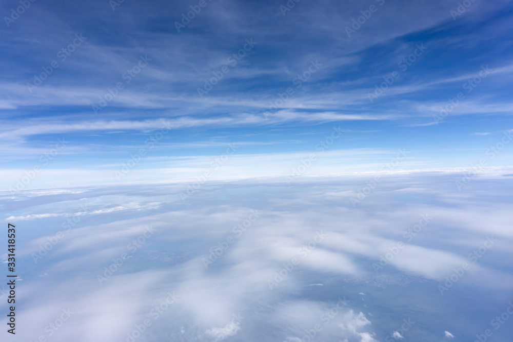Skyscape view from clear glass window seat from aircraft to cloudscape, traveling on white fluffy clouds and vivid blue sky in a suny day
