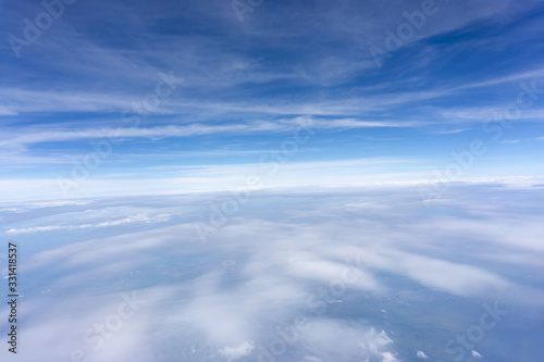 Skyscape view from clear glass window seat from aircraft to cloudscape  traveling on white fluffy clouds and vivid blue sky in a suny day
