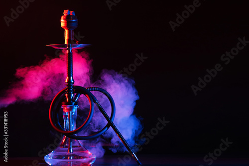 glass hookah shisha with a metal bowl on the table on a black background with smoke photo