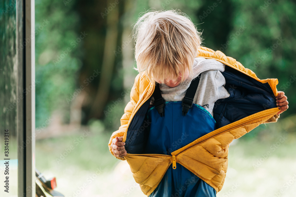 Kleinkind in Regenhose zieht seine Jacke aus Stock Photo | Adobe Stock