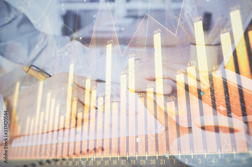 Multi exposure of stock market graph with man working on laptop on background. Concept of financial analysis.